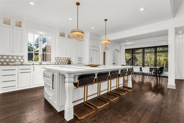 a kitchen with stainless steel appliances granite countertop a stove a sink a island with a dining table and chairs