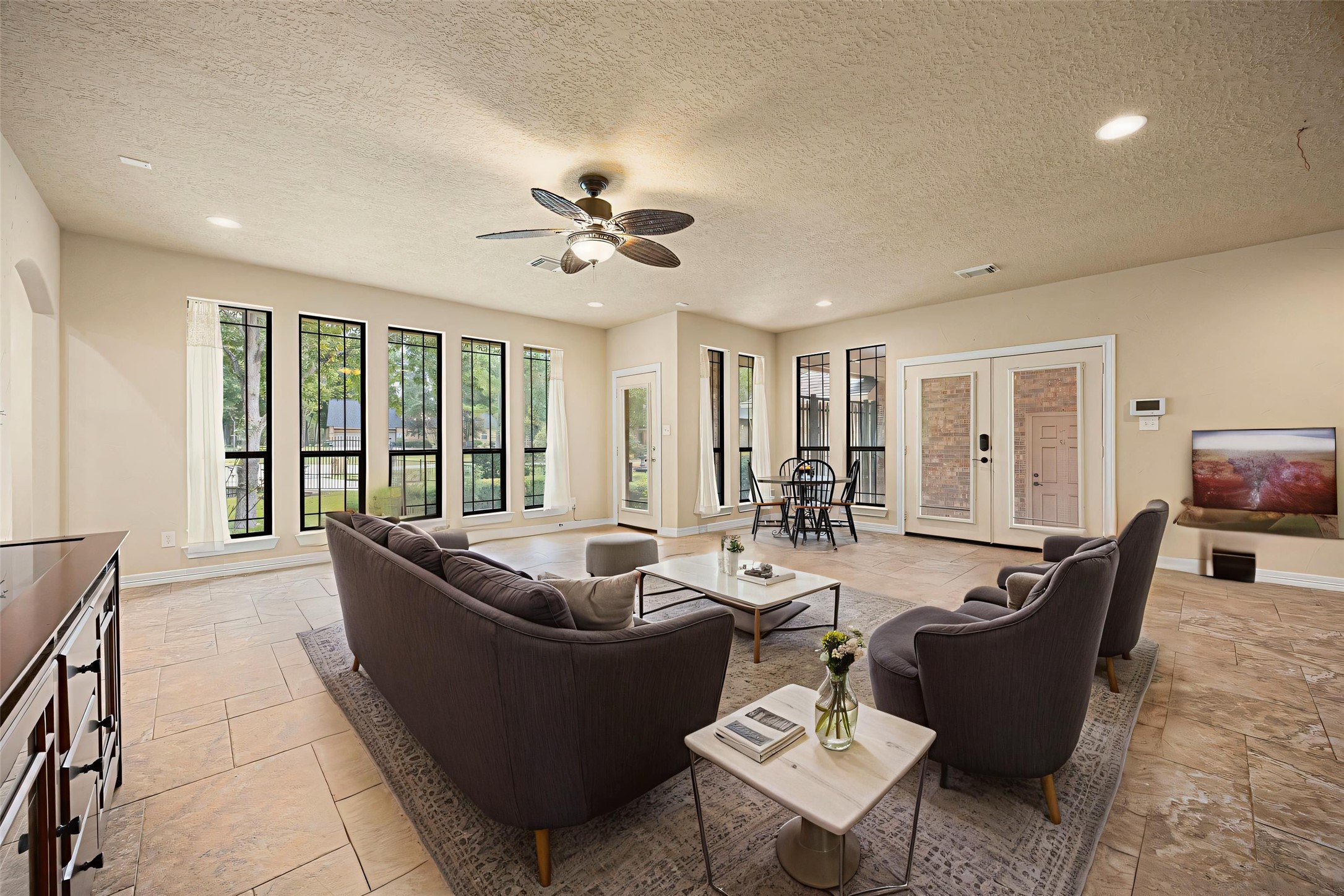 28618 Benders Crossing Drive Spring, TX 77386 - Photo 17 of 46 Light-filled living room featuring expansive windows, recessed lighting, and a ceiling fan for comfort. Abundant natural light and views of the surrounding greenery create a warm, inviting atmosphere with seamless access to the outdoor living areas.
