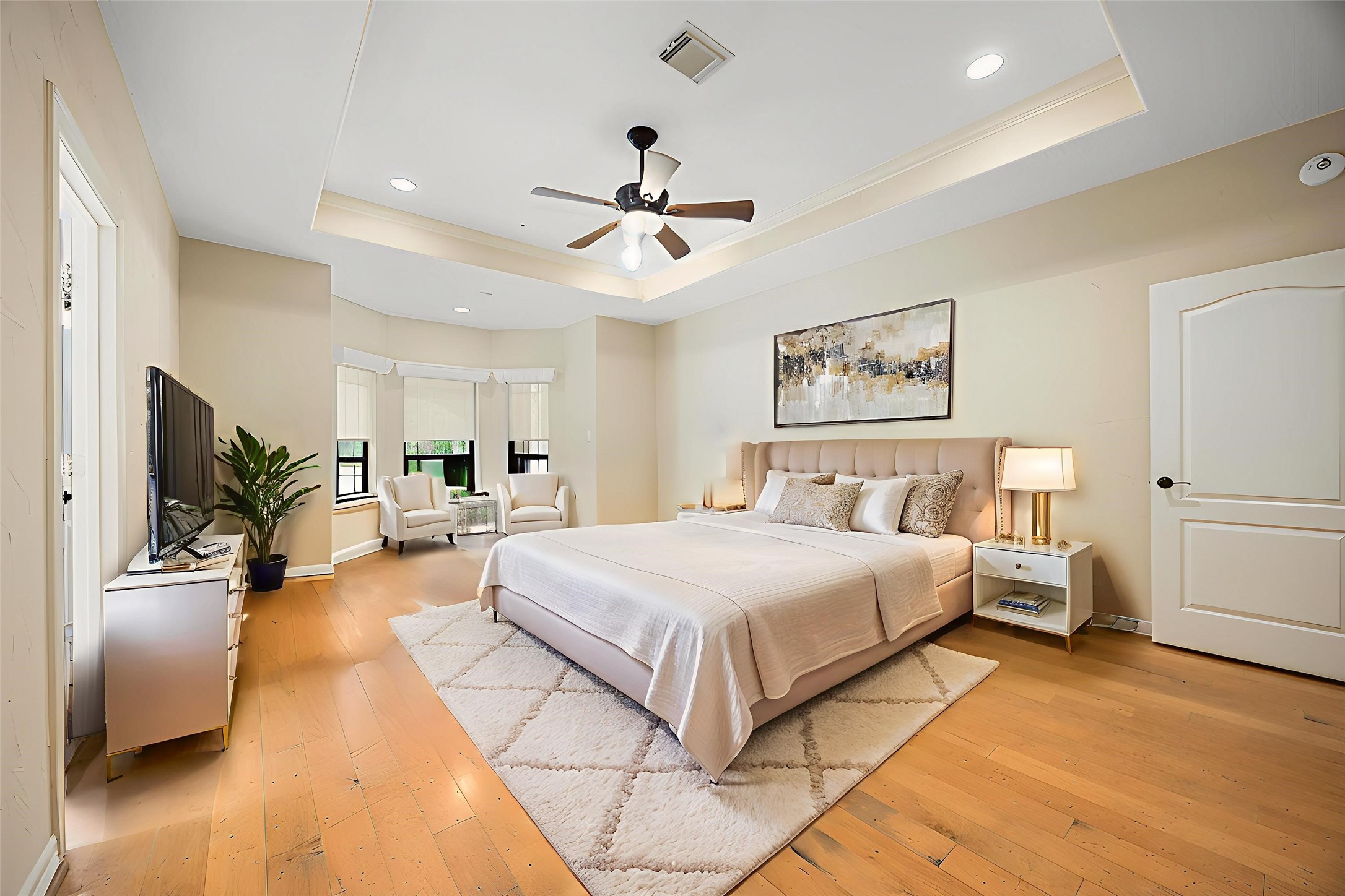 28618 Benders Crossing Drive Spring, TX 77386 - Photo 20 of 46 Spacious primary bedroom featuring a tray ceiling with recessed lighting, ceiling fan, and hardwood flooring. A cozy sitting area and generous natural light create a peaceful retreat designed for comfort and relaxation.