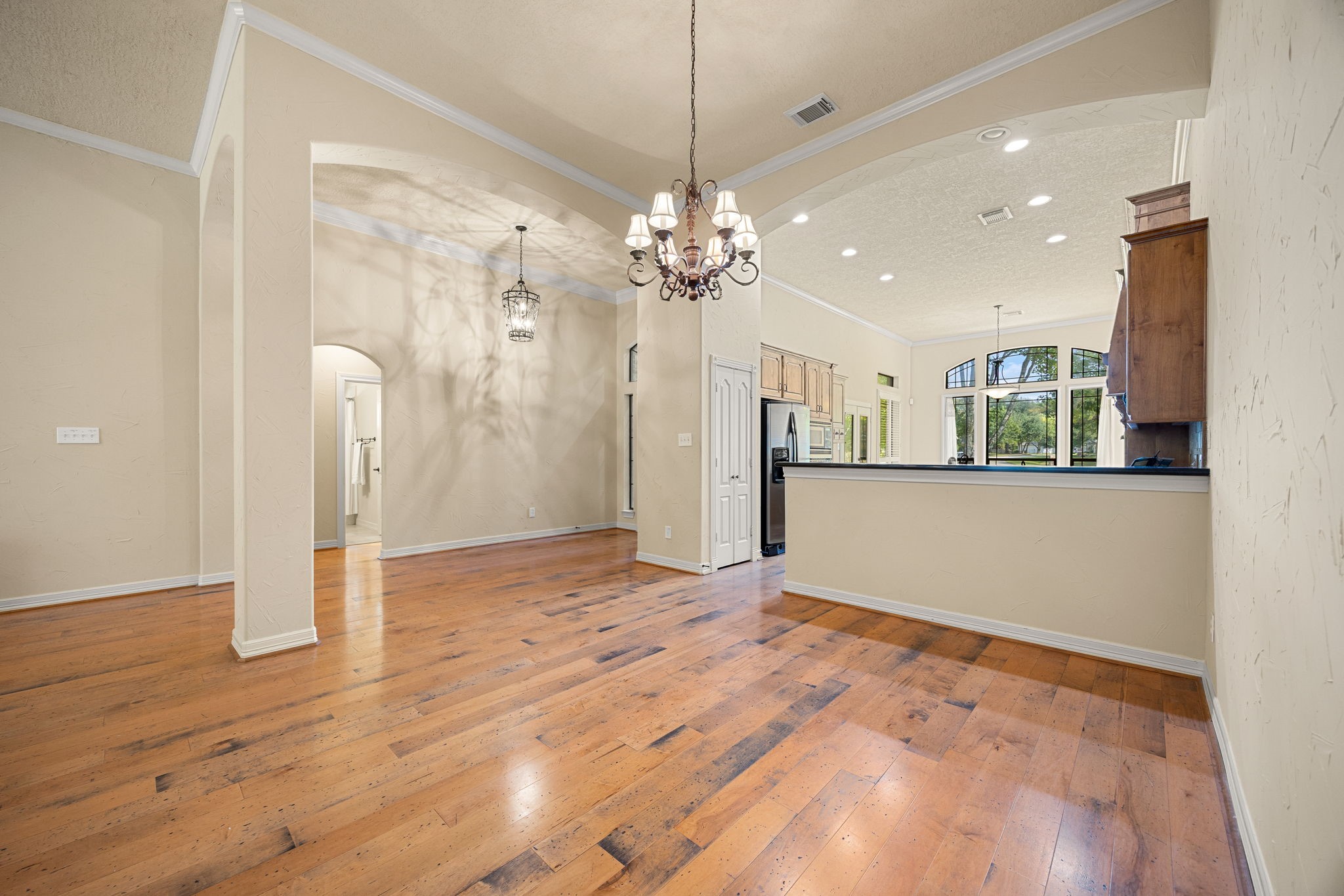 28618 Benders Crossing Drive Spring, TX 77386 - Photo 23 of 46 Expansive open living and dining area featuring hardwood flooring, elegant archways, and chandelier lighting. Designed for flexible furniture placement and effortless entertaining.