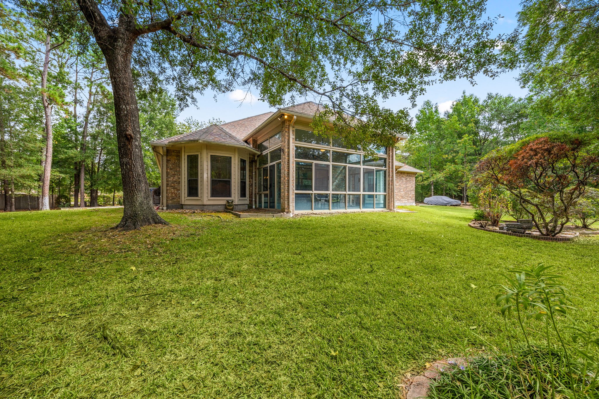 28618 Benders Crossing Drive Spring, TX 77386 - Photo 35 of 46 Spacious backyard with mature trees and lush lawn, offering a peaceful outdoor setting. Expansive views of the enclosed sunroom highlight seamless indoor–outdoor connection.