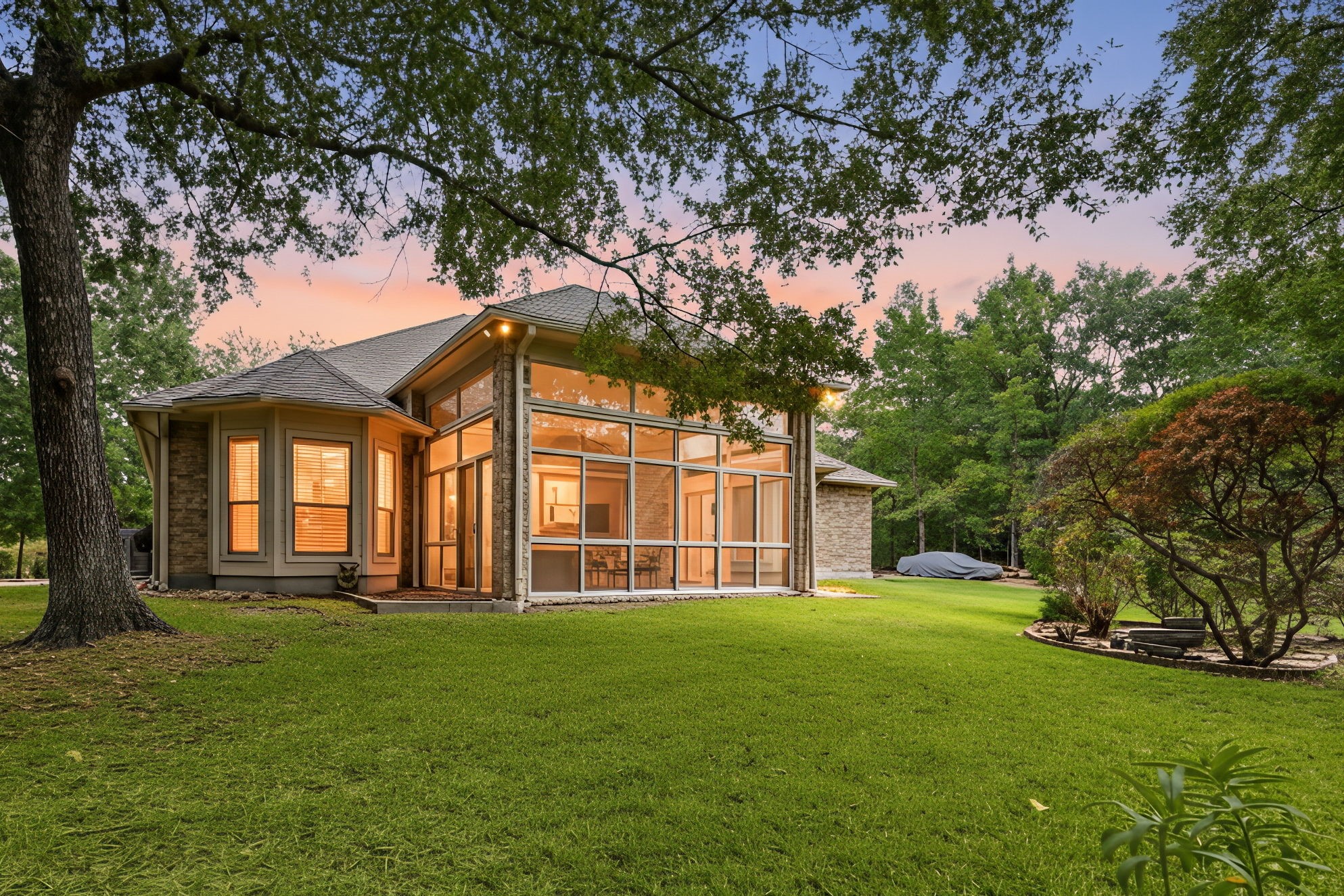 28618 Benders Crossing Drive Spring, TX 77386 - Photo 37 of 46 Serene twilight view of the private backyard highlighting the home’s expansive glass-enclosed sunroom. Floor-to-ceiling windows flood the interior with natural light while offering peaceful views of the surrounding mature trees, creating an ideal space for year-round enjoyment and outdoor living.