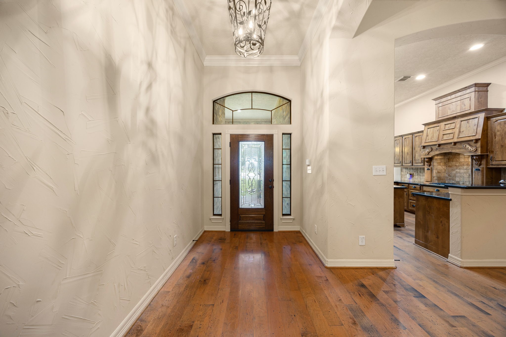 28618 Benders Crossing Drive Spring, TX 77386 - Photo 7 of 46 Elegant formal entry featuring textured walls, custom front door with decorative glass, and transom window allowing natural light to pour in. Rich hardwood flooring and refined architectural details set a warm and welcoming tone upon entry.