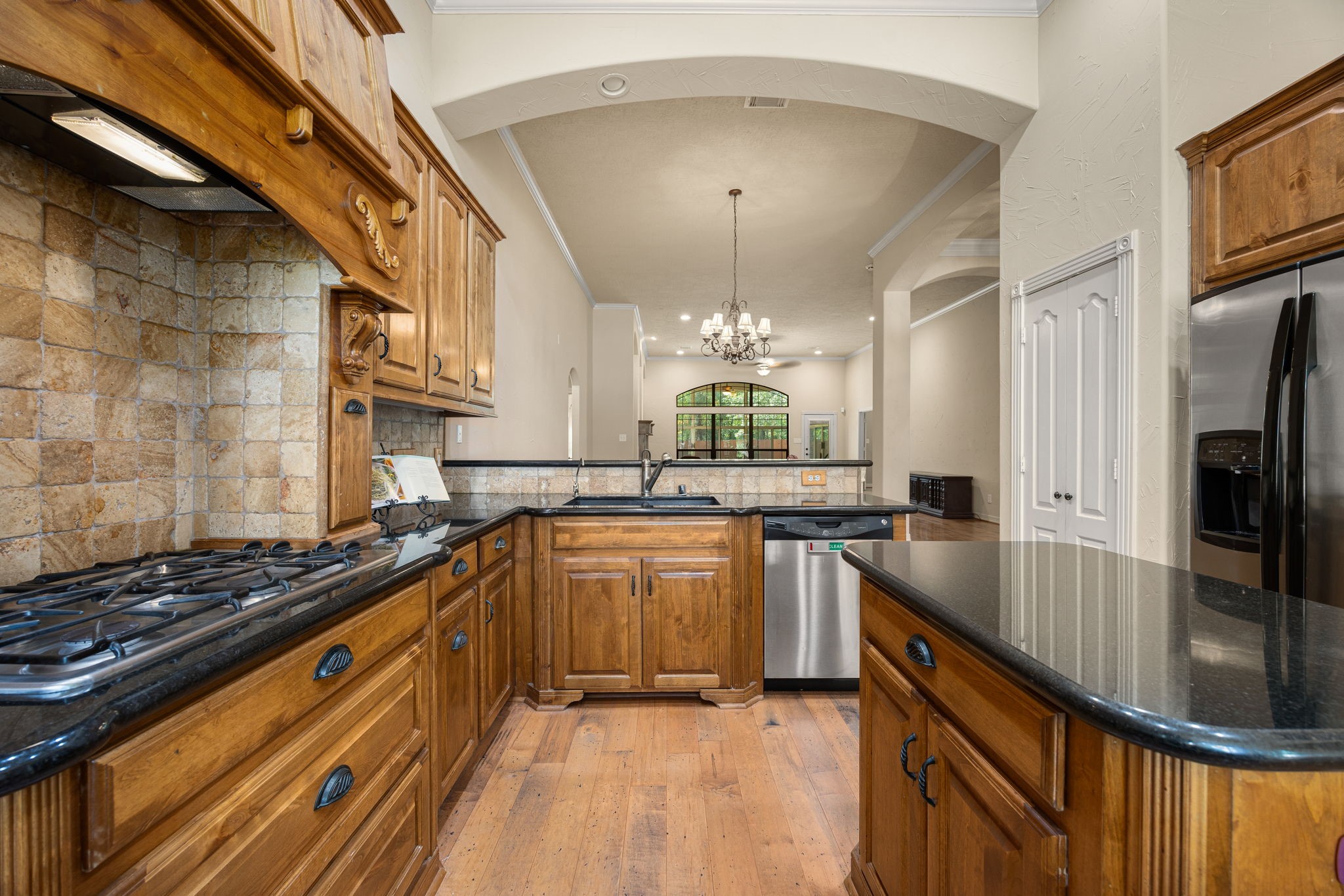 28618 Benders Crossing Drive Spring, TX 77386 - Photo 9 of 46 Well-appointed kitchen offering abundant cabinetry, granite countertops, gas cooktop, and stainless steel appliances. Open arches and extended sightlines connect seamlessly to the main living areas, enhancing both functionality and entertaining appeal.
