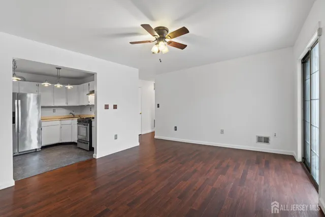 a view of an empty room with a window and wooden floor