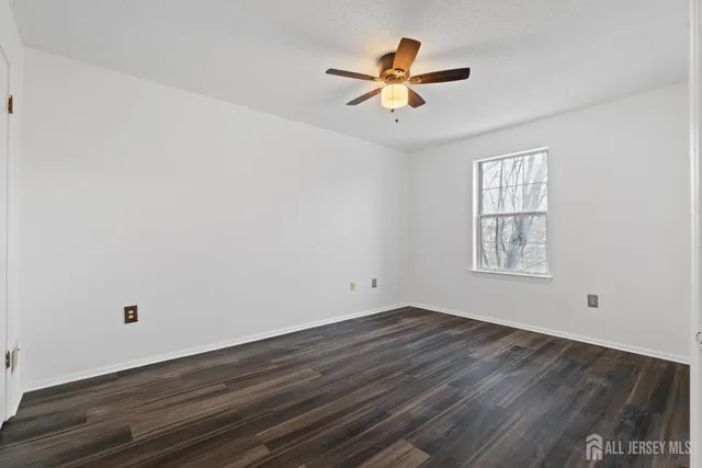 an empty room with wooden floor fan and windows