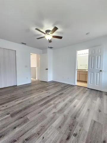 a view of empty room with wooden floor and fan