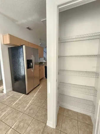 a view of a refrigerator in kitchen and an empty room