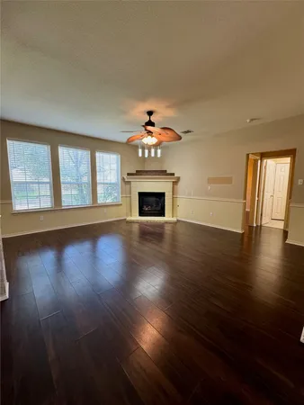 a view of an empty room with wooden floor fireplace and a window