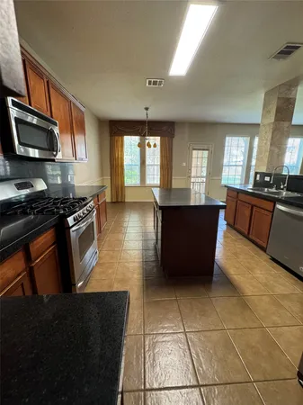 a kitchen with stainless steel appliances granite countertop a stove a sink and a microwave