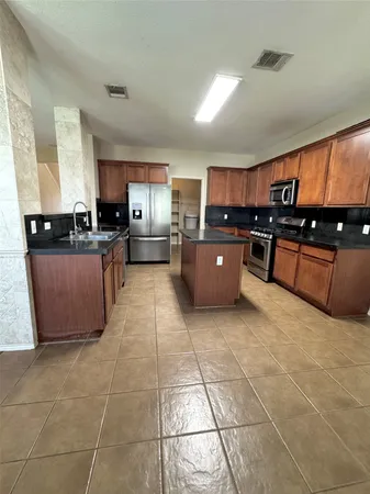 a large kitchen with granite countertop a stove a sink a counter space and cabinets