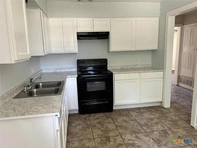 a kitchen with granite countertop a stove sink and cabinets