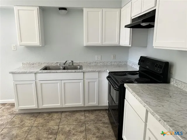 a kitchen with granite countertop white cabinets and black appliances