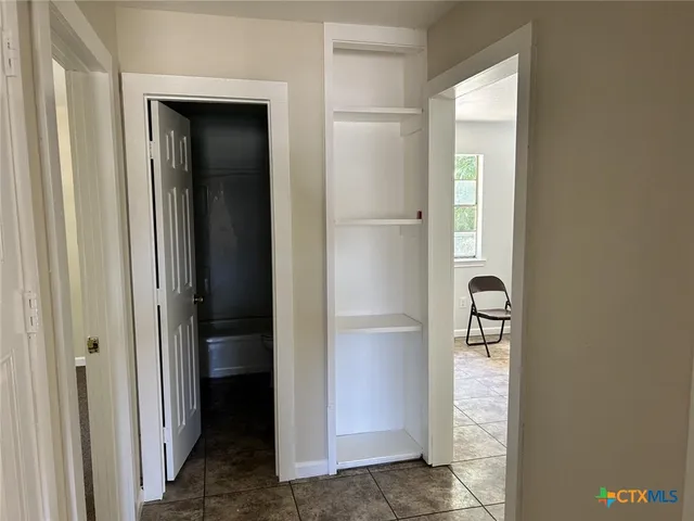 a view of a hallway with closet and a bathroom