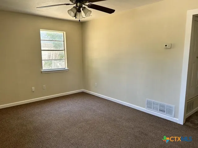 an empty room with a window and a ceiling fan