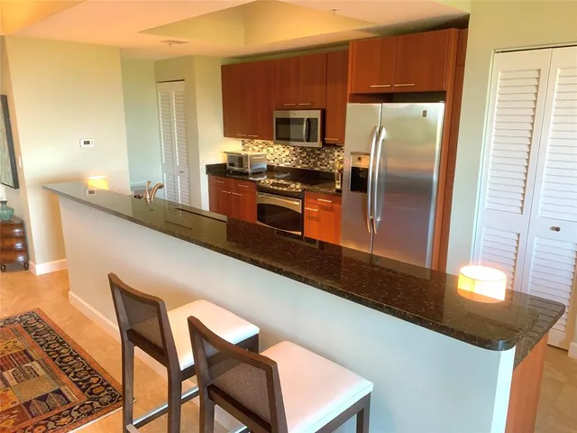 a kitchen with stainless steel appliances granite countertop a sink and a refrigerator