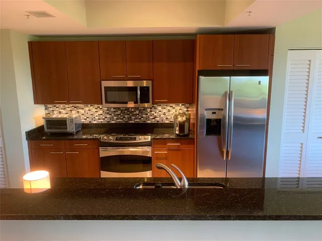 a kitchen with granite countertop a stove refrigerator and microwave