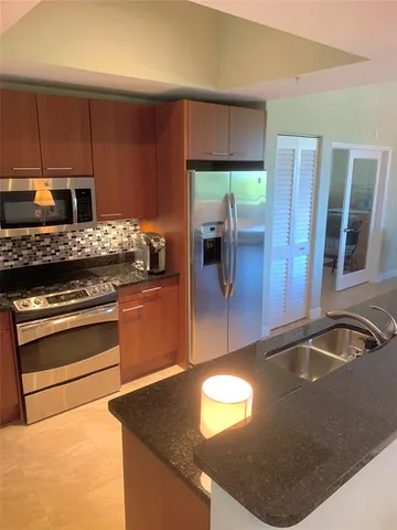 a kitchen with kitchen island granite countertop a sink stove and refrigerator