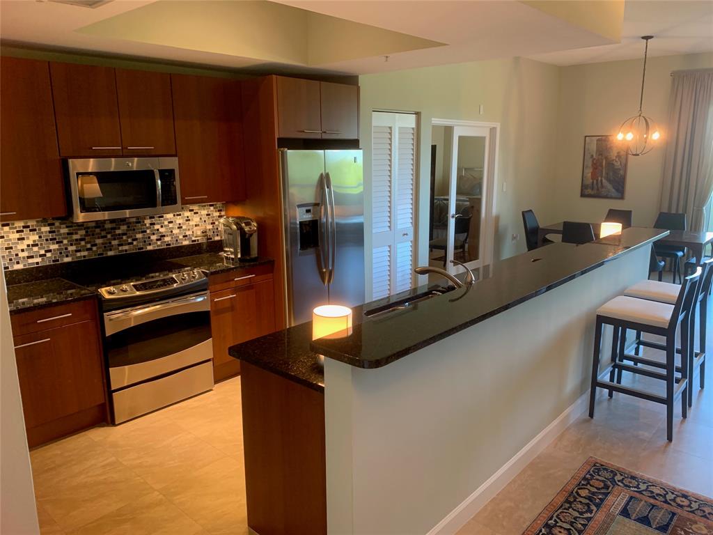 2301 Wilton Drive, Unit R409 Wilton Manors, FL 33305 - Photo 10 of 38 a kitchen with stainless steel appliances kitchen island granite countertop a stove a refrigerator and a dining table with granite countertops