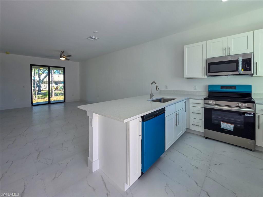 4814 30th Street Southwest Lehigh Acres, FL 33973 - Photo 2 of 11 a kitchen with stainless steel appliances granite countertop a stove a sink and a microwave