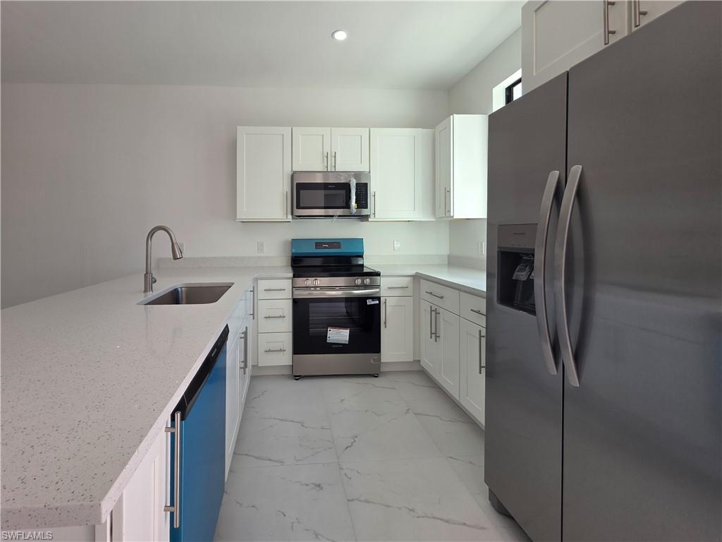 4814 30th Street Southwest Lehigh Acres, FL 33973 - Photo 3 of 11 a kitchen with stainless steel appliances a refrigerator sink and microwave