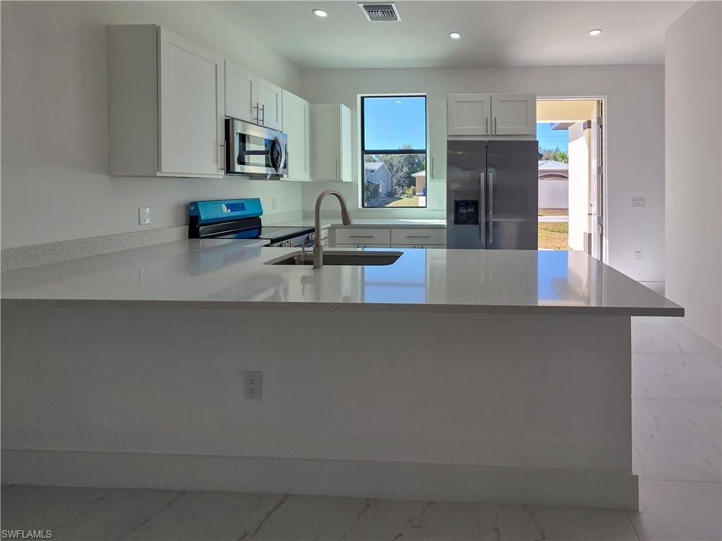 4814 30th Street Southwest Lehigh Acres, FL 33973 - Photo 4 of 11 a kitchen with kitchen island a refrigerator a stove a sink a counter space and cabinets