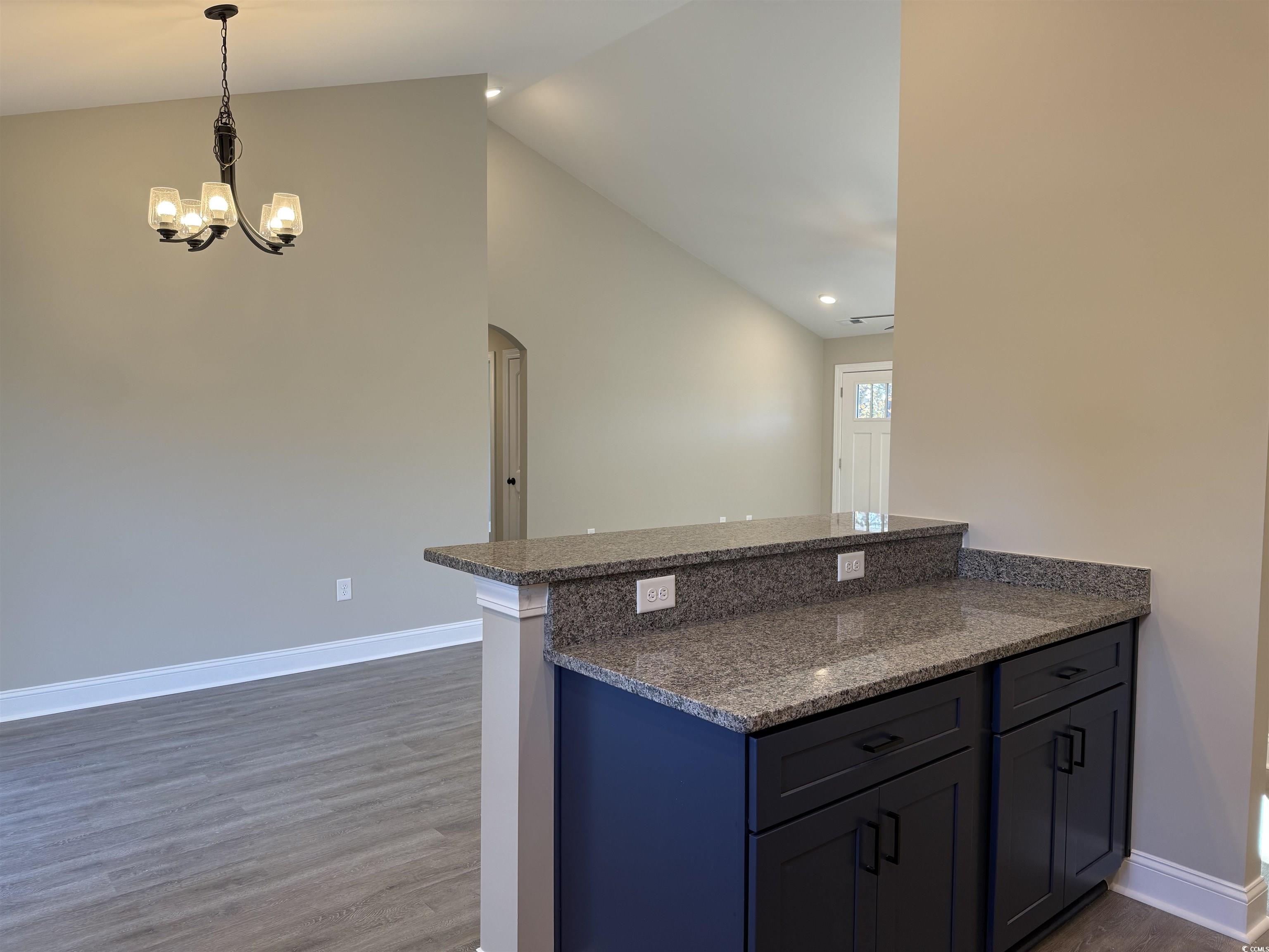 242 Country Club Road Marion, SC 29571 - Photo 18 of 33 Kitchen featuring dark stone countertops, arched walkways, dark wood-style floors, pendant lighting, and a peninsula