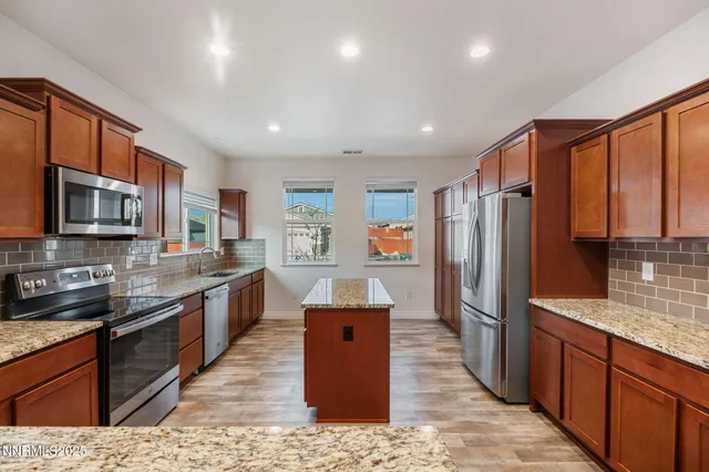 a kitchen with stainless steel appliances granite countertop a refrigerator a stove top oven and a sink