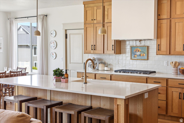 283 North 500 West Mapleton, UT 84664 - Photo 26 of 102 Kitchen with a breakfast bar area, range hood, tasteful backsplash, and light quartz countertops.