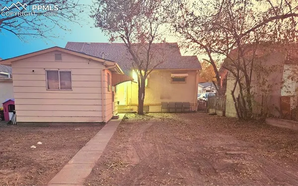 a backyard of a house with large trees and brick walls