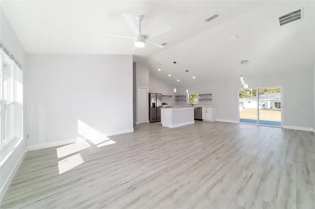 a view of kitchen with kitchen island a sink wooden floor and a refrigerator