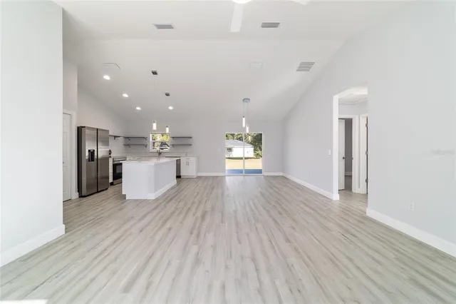 a view of an empty room with wooden floor and a large window
