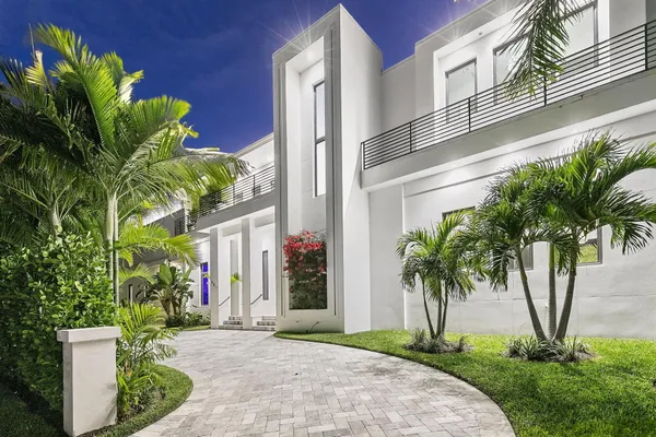 a view of a white building with a garden and plants