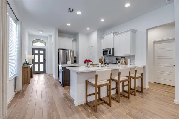 a kitchen with cabinets a sink dishwasher a dining table and chairs with wooden floor