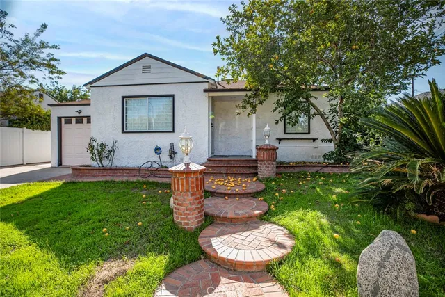 a view of a backyard with table and chairs potted plants and large tree
