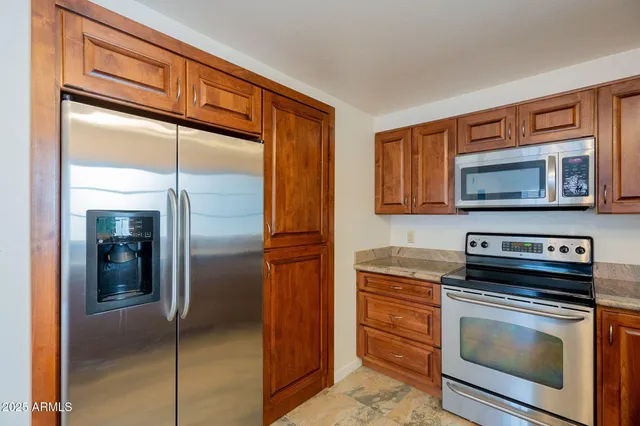 a kitchen with stainless steel appliances granite countertop a refrigerator and a stove top oven