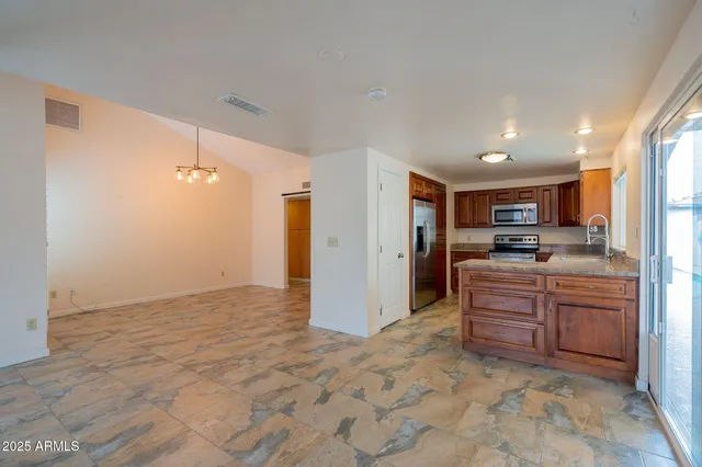 a large kitchen with stainless steel appliances granite countertop a refrigerator and a stove top oven