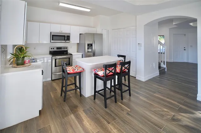 a kitchen with stainless steel appliances a dining table chairs stove refrigerator and microwave