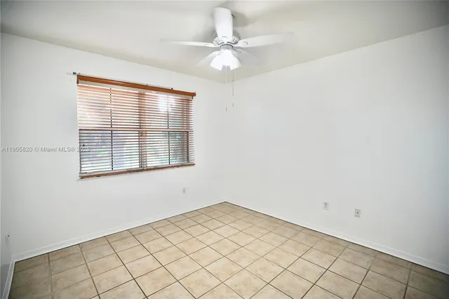 an empty room with windows and ceiling fan