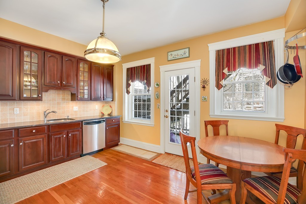 94 University Road, Unit 3 Brookline, MA 02446 - Photo 5 of 20 a kitchen with stainless steel appliances granite countertop a stove a sink dishwasher a dining table and chairs with wooden floor