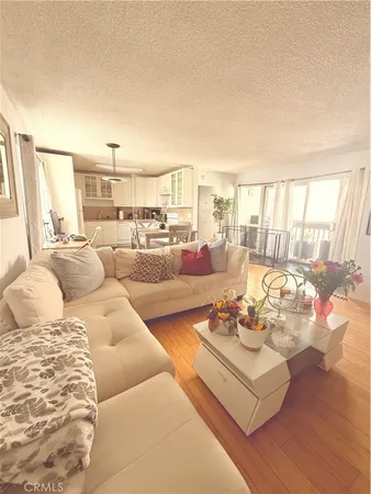 a view of a kitchen with kitchen island stainless steel appliances wooden floor dining table and chairs