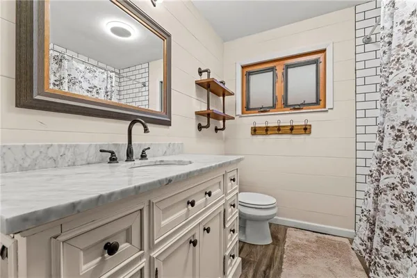 a bathroom with a granite countertop sink mirror vanity and toilet