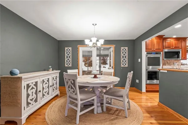 a dining area with furniture a chandelier and wooden floor
