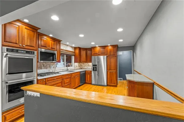 a kitchen with stainless steel appliances granite countertop a sink a stove and a refrigerator