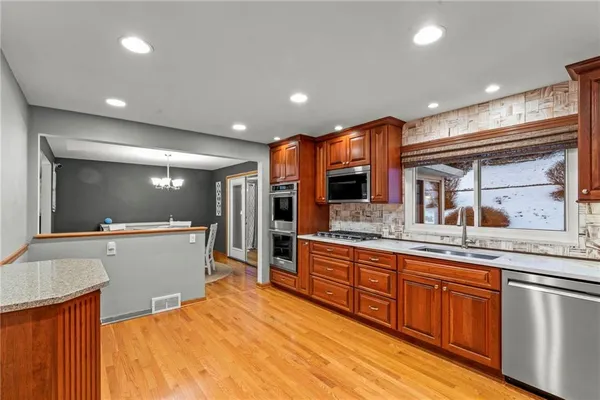 a large kitchen with stainless steel appliances a large counter top a stove and a sink