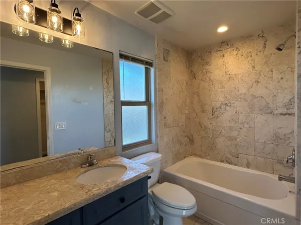 a bathroom with a granite countertop sink a toilet and bathtub