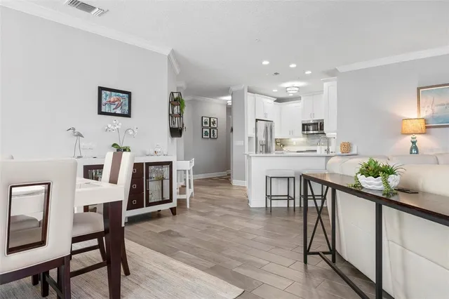 a kitchen with stainless steel appliances kitchen island granite countertop a refrigerator a stove a dining table and chairs with wooden floor