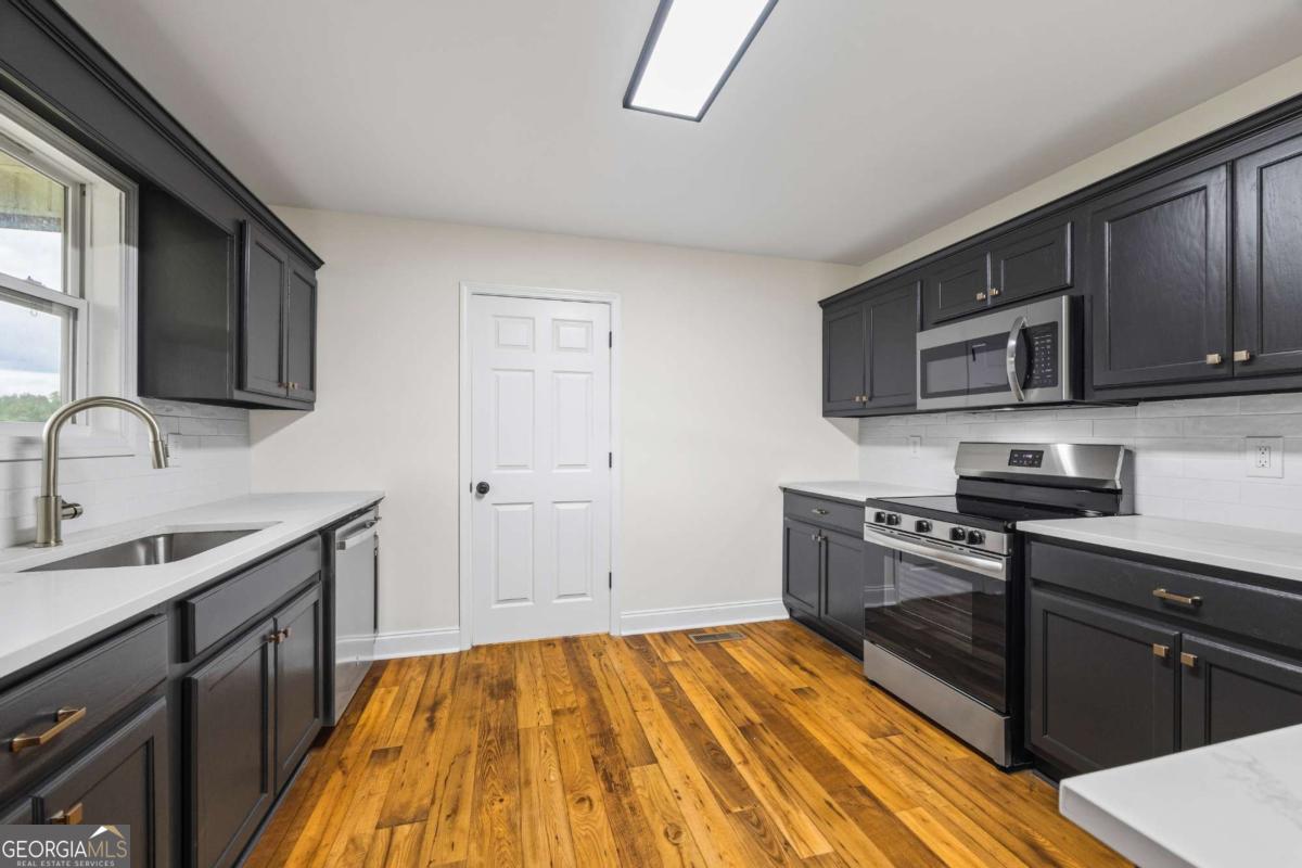 1718 Ed Bennett Road Nicholson, GA 30565 - Photo 29 of 71 a kitchen with stainless steel appliances wooden cabinets and a stove top oven