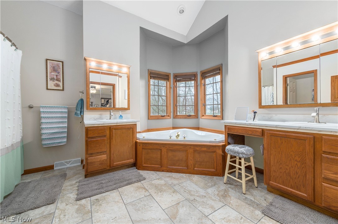 44565 Stang Road Elyria, OH 44035 - Photo 22 of 50 Bathroom with a bath, two vanities, lofted ceiling, and a shower with curtain