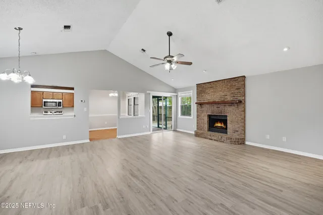 a view of an empty room with wooden floor and a fireplace